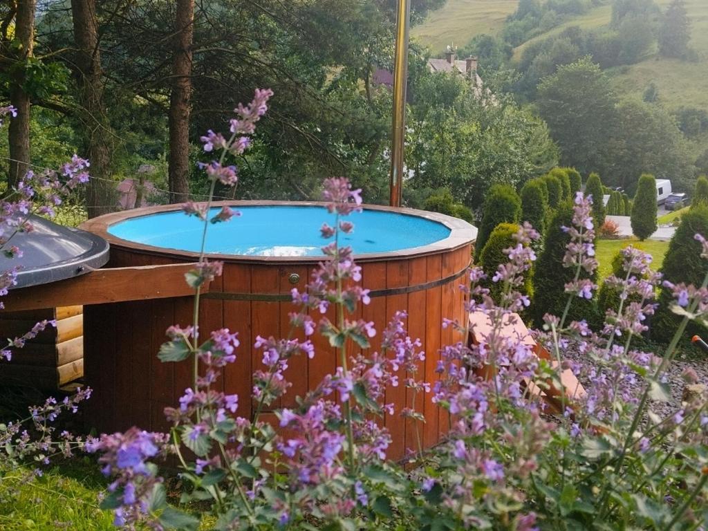 a hot tub in a garden with purple flowers at Domek Sielski Zakątek Pieniny in Szczawnica