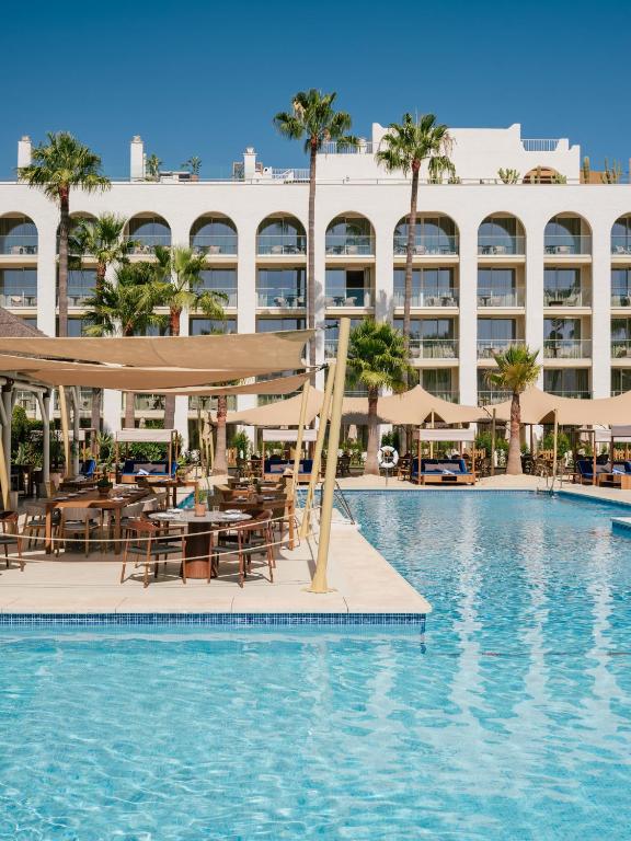 a swimming pool with tables and umbrellas next to a hotel at ME by Meliá Marbella in Marbella