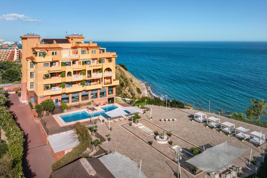 a building on a cliff next to the ocean at Holiday World Casamaïa Apartments, Affiliated by Meliá in Benalmádena