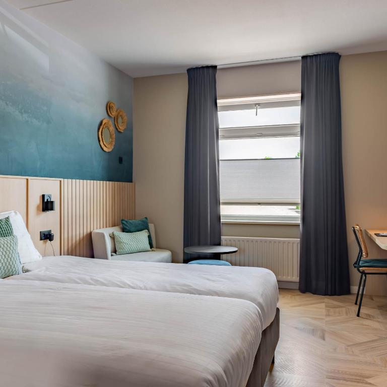 a hotel room with two beds and a window at Hotel de Gentsche Poort in Biervliet