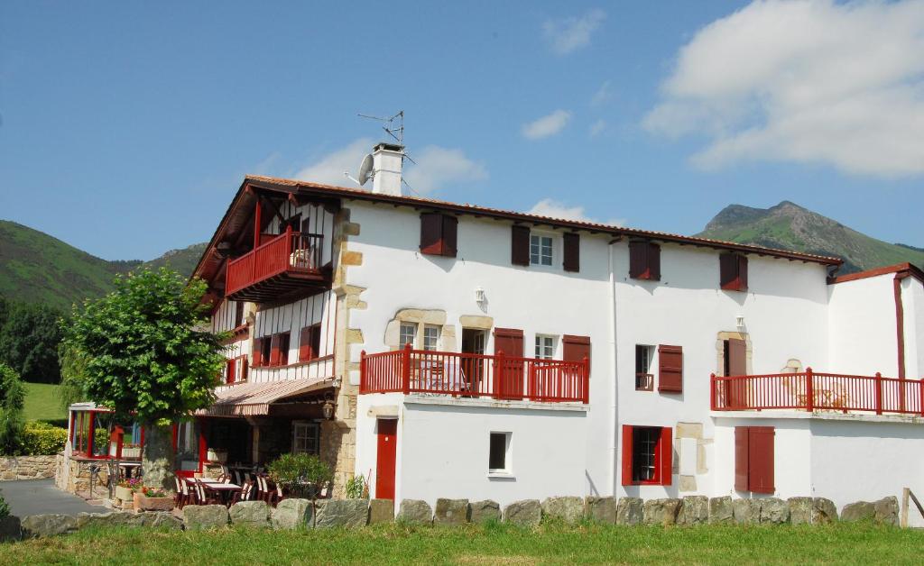 un gran edificio blanco con balcones rojos. en Hotel Pikassaria, en Sare