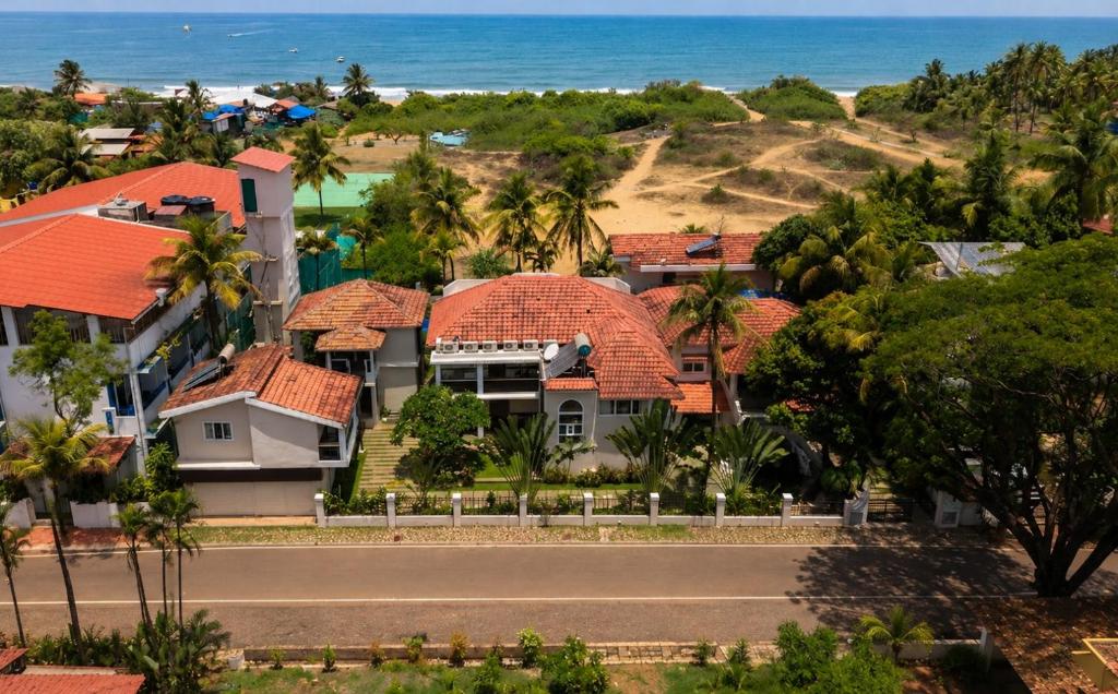 a house with a road in front of the ocean at Resort Coqueiral - A Portuguese Heritage Stay by the Sea in Candolim