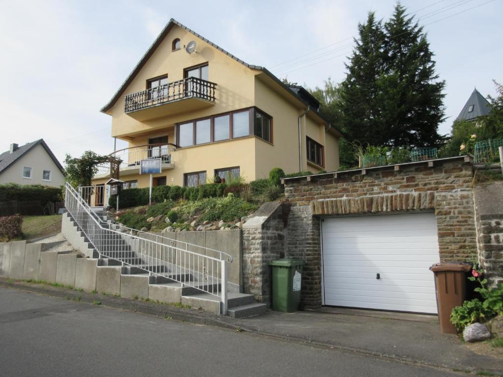 a large yellow house with a garage and stairs at Haus Linn in Hachenburg