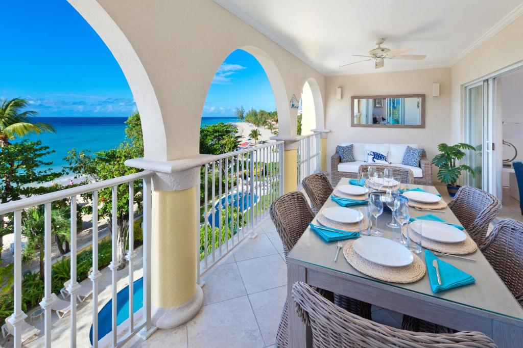 a dining table on a balcony with a view of the ocean at Modern Beachfront Condo with Pool - Sapphire 307 in Christ Church