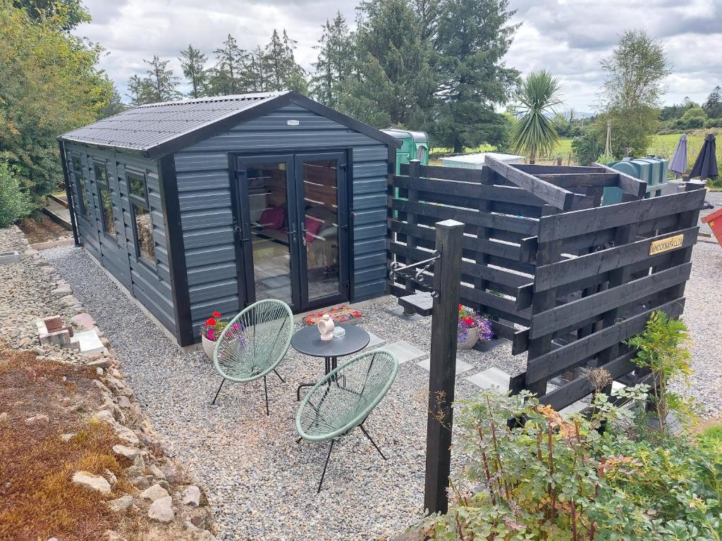 a black shed with a table and chairs in a garden at Knocknafallia in Cappoquin