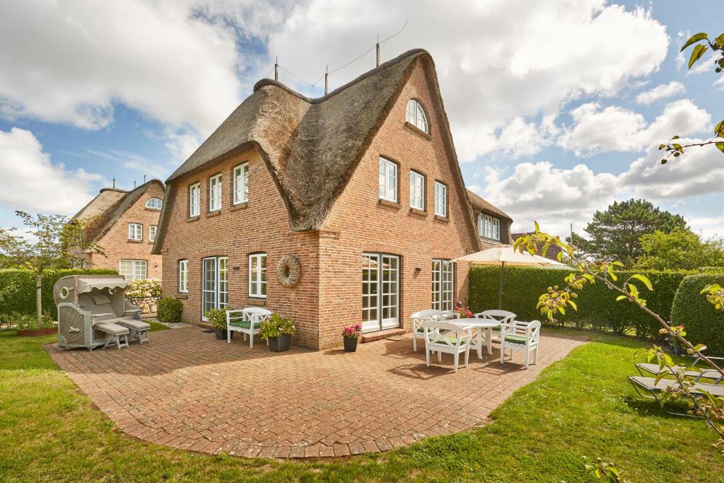 a large brick building with a patio and tables at Haus Amrumblick in Hedehusum
