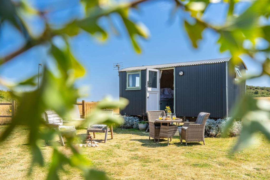 a caravan with chairs and a table in a yard at Saltmarsh Hut in Stiffkey