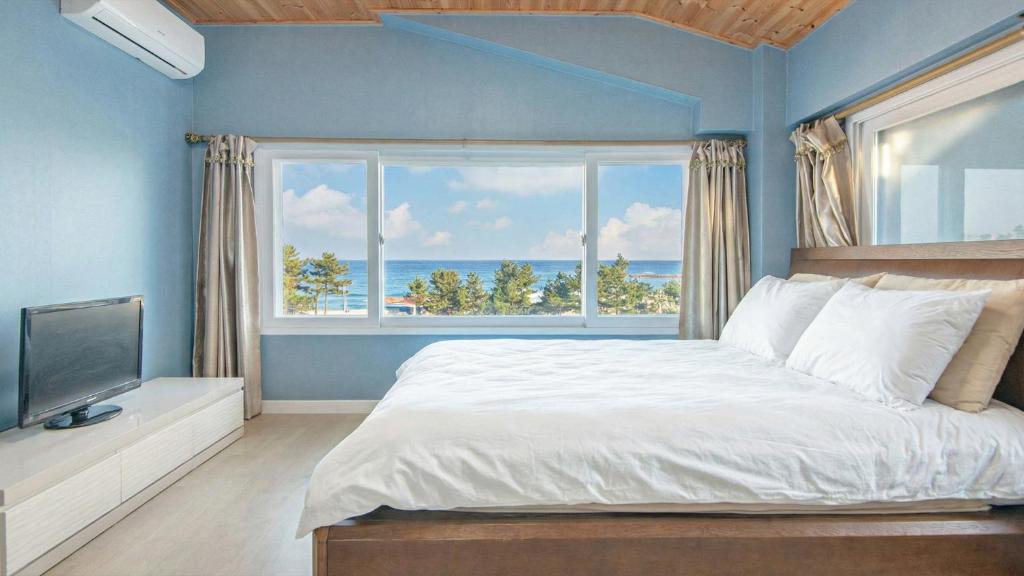 a bedroom with a large bed and a large window at Goseong Omaju Pension in Goseong