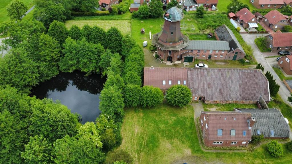 an aerial view of a village with a house and a pond at Mühlenhof Nesse in Dornum
