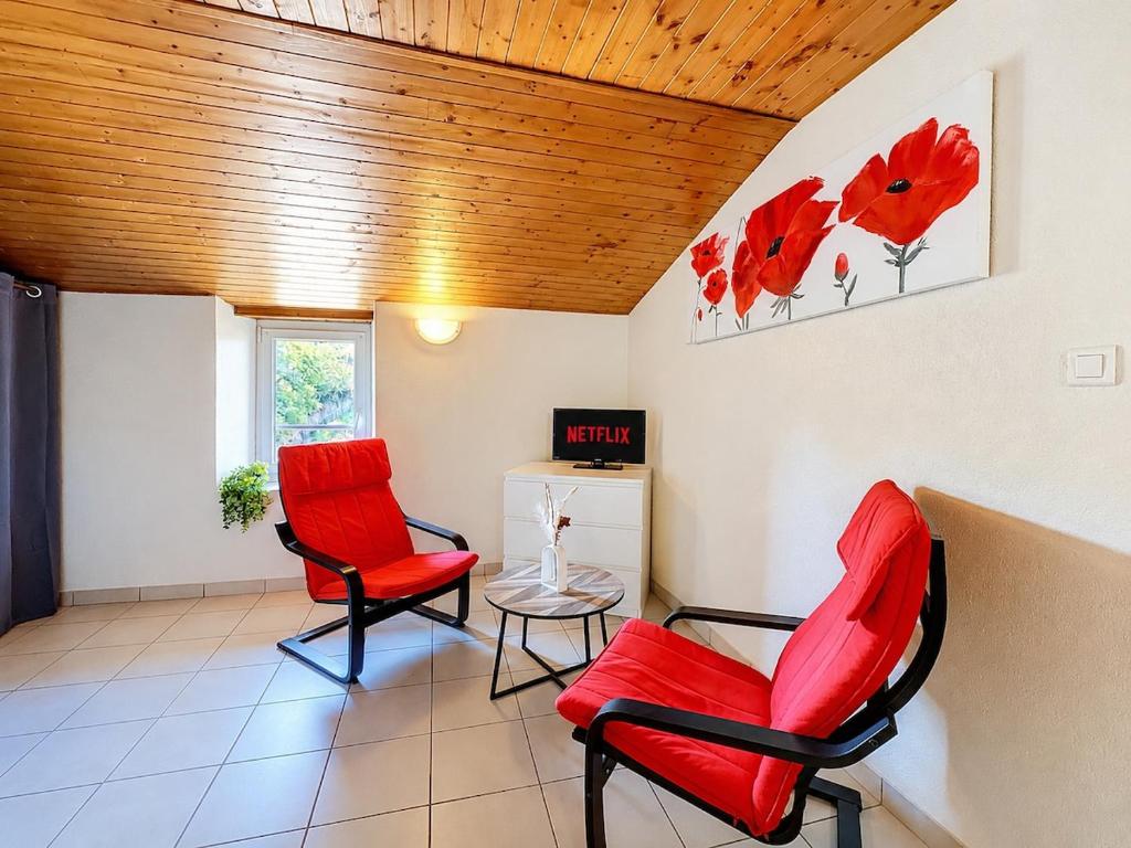 two red chairs and a table in a room at Le Cornas in Vérin