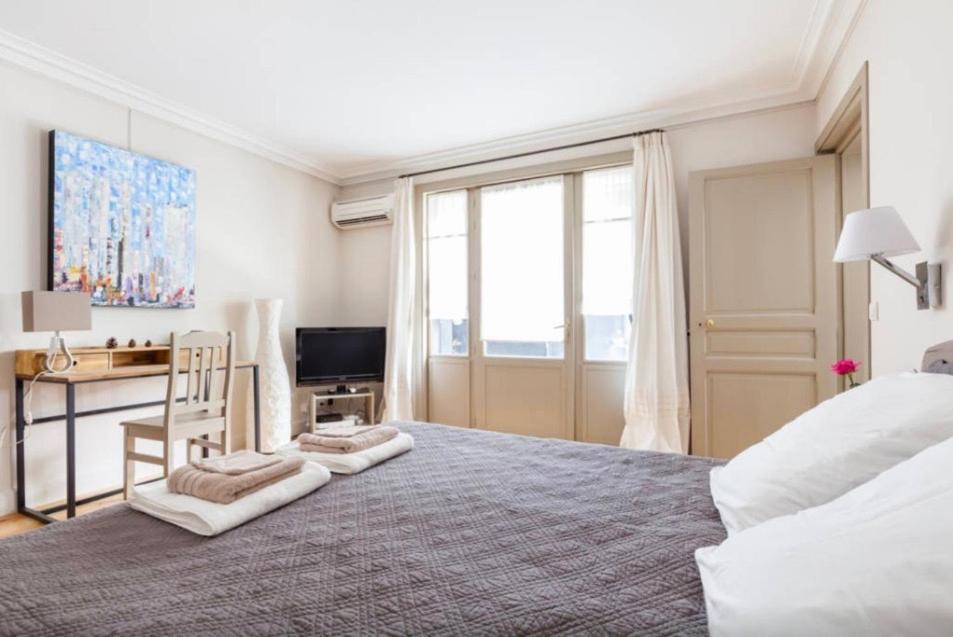 a bedroom with a large bed with a desk and a television at 1 Square du Docteur Blanche - Paris 16 in Paris