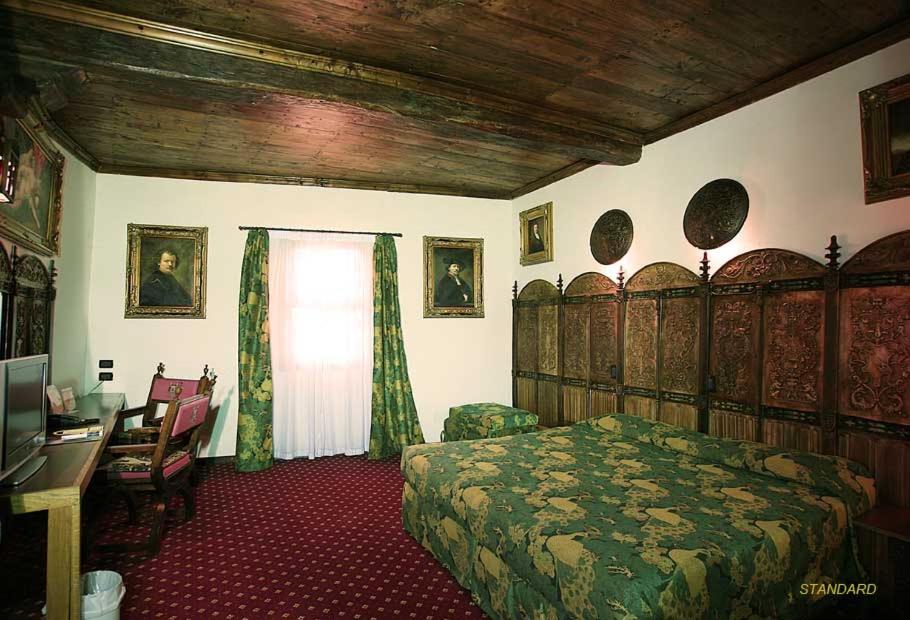 a bedroom with a bed and a desk and a window at Castello Di Pavone in Pavone Canavese