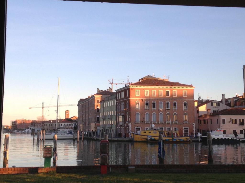 un fiume con edifici e una barca in acqua di Casa Franca a Chioggia