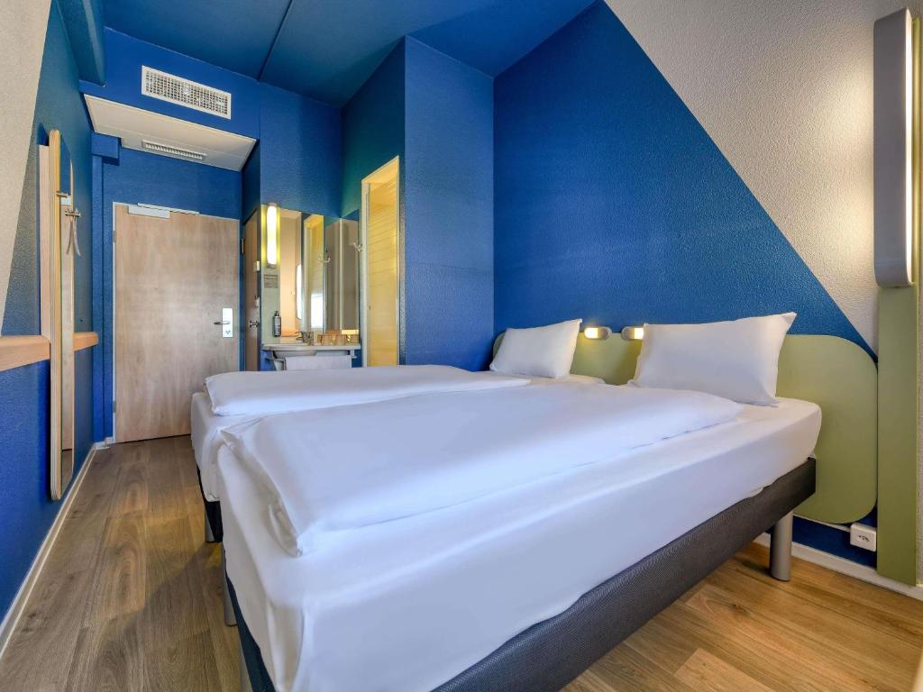 a large white bed in a room with a blue wall at ibis budget Hotel Luzern City in Lucerne