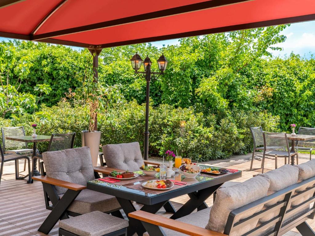a patio with a table and chairs under a red umbrella at Ibis Bursa in Bursa