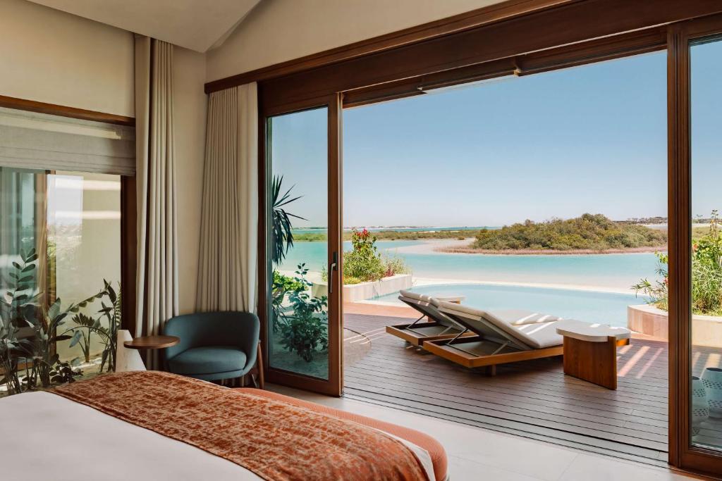 a bedroom with a bed and a view of the ocean at Miraval The Red Sea All Inclusive Adults Only in Ḩanak