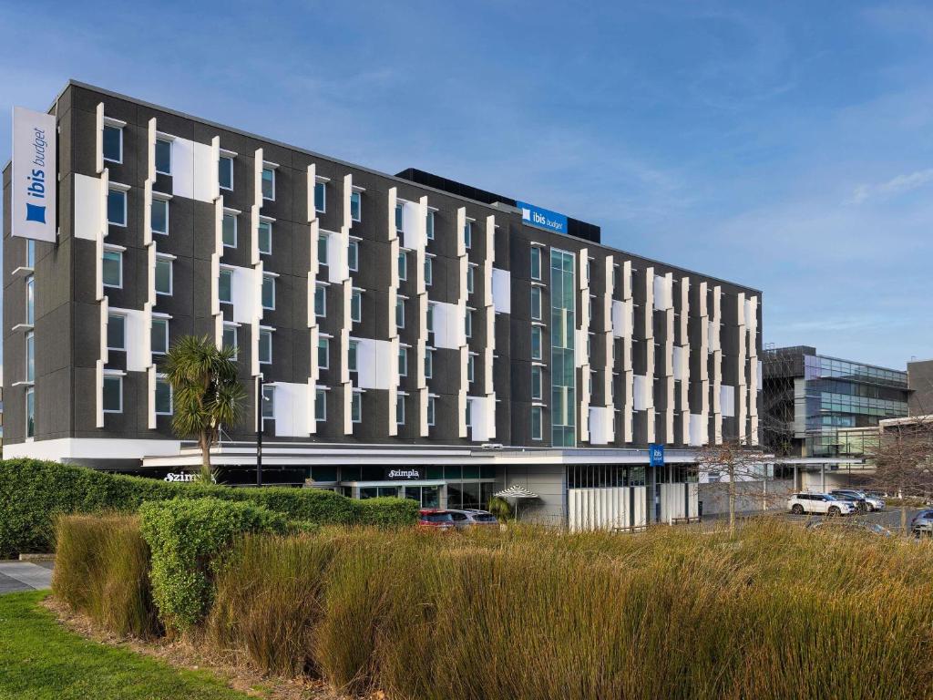 a large building with white windows in a parking lot at ibis Budget Auckland Airport in Auckland