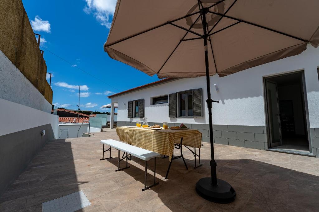 an umbrella on a patio with a table and chairs at Casa Turalves - By WeHostMadeira in Porto Santo