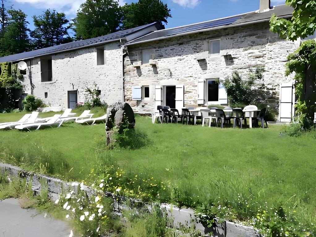 a stone building with chairs and tables in a yard at Gîte proche de La Salvetat in Le Soulié