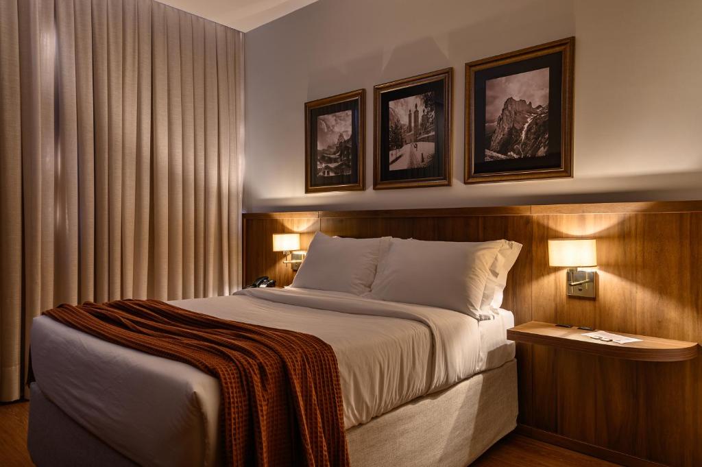 a hotel room with a large bed with two lamps at Hotel Maerkli in Santo Ângelo