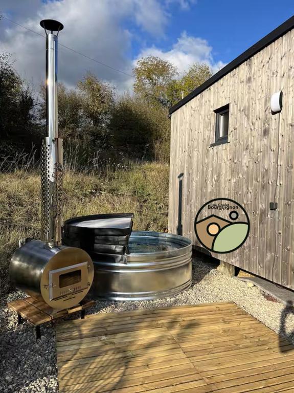 a hot tub and a grill next to a wooden building at Au Chalet Bourguignon 4 in Salives