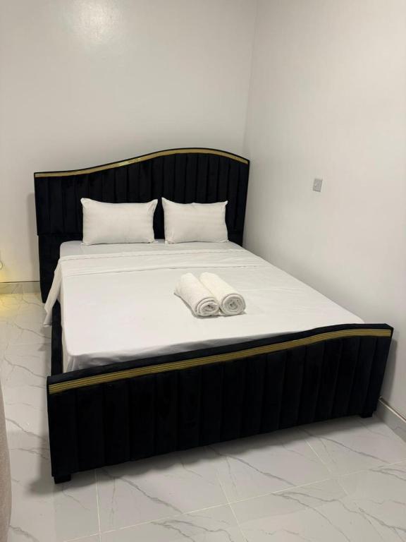 a bed with a black frame with two towels on it at Coastal comfort studio apartment in Mombasa