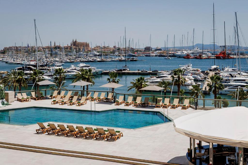 a pool with chairs and a marina with boats at Meliá Palma Marina in Palma de Mallorca