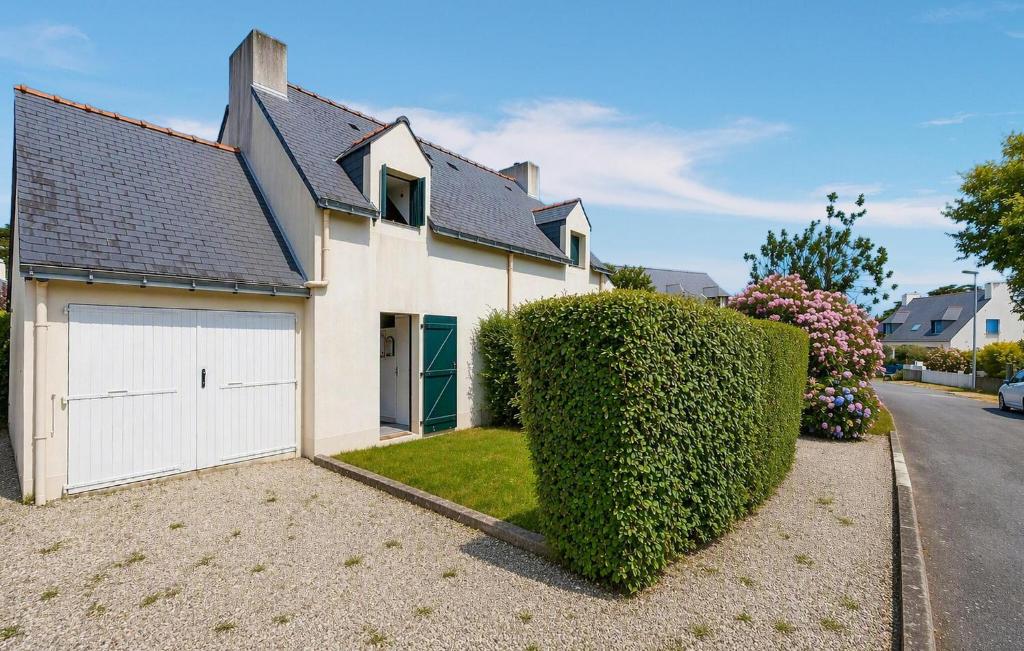 a white house with a garage and a hedge at Maison Piriac in Piriac-sur-Mer