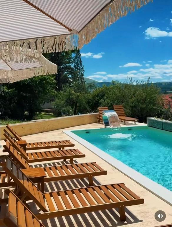 a swimming pool with chairs and an umbrella at Apartman M306 Zlatibor in Palisat