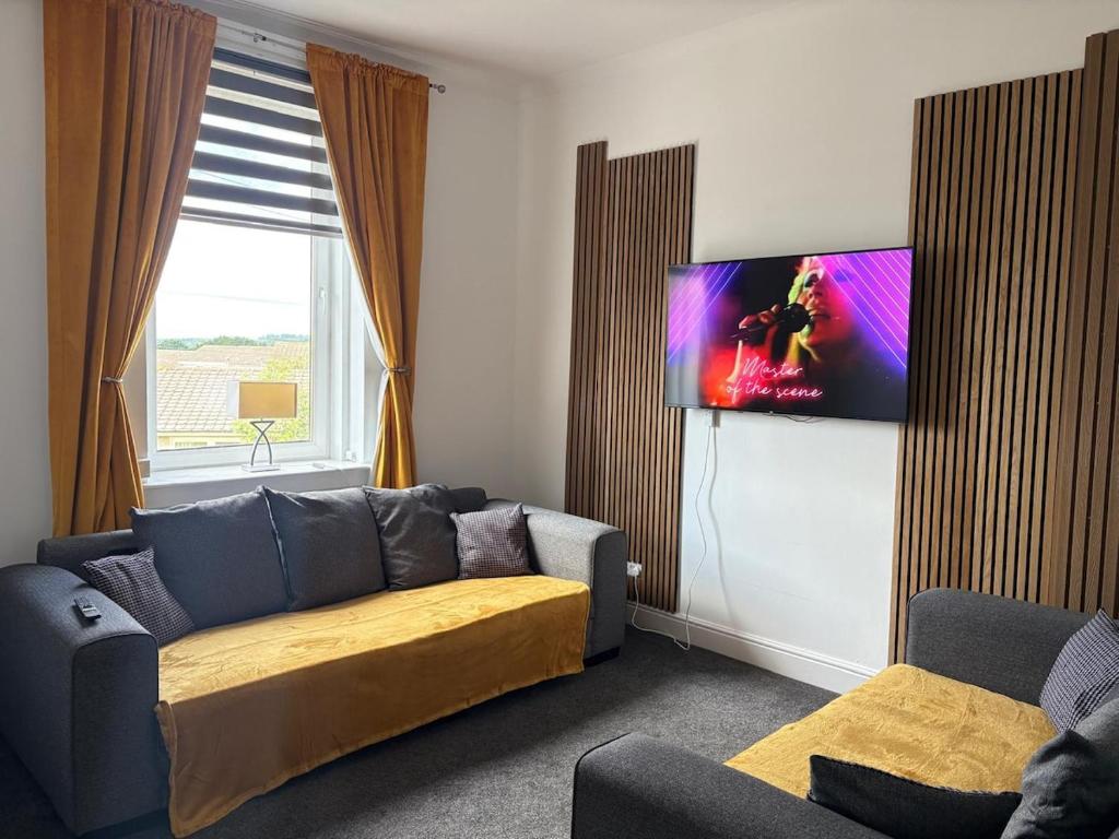 a living room with a couch and a tv on the wall at The M Rooms at 158 in Shotts Station