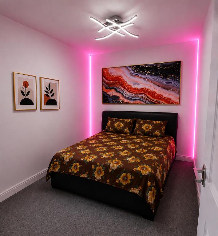 a bedroom with a bed with a pink lighting at The Peaceful Home in Nottingham