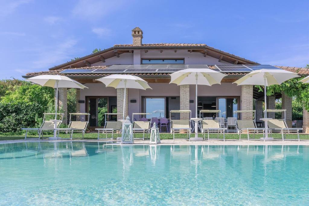 a house with a swimming pool with chairs and umbrellas at Villa Sara in San Costanzo