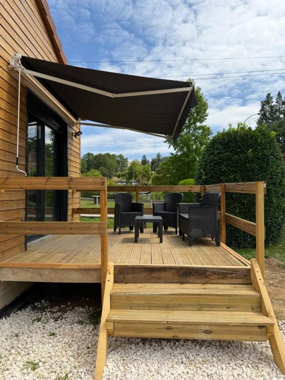 a wooden deck with a black canopy and chairs at Chalet Jean Leclaire in Sarlat-la-Canéda