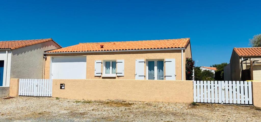 a house with a white fence in front of it at La Fleur des Marais - Maison tout confort au calme, grand jardin & balançoire in Le Château-dʼOléron