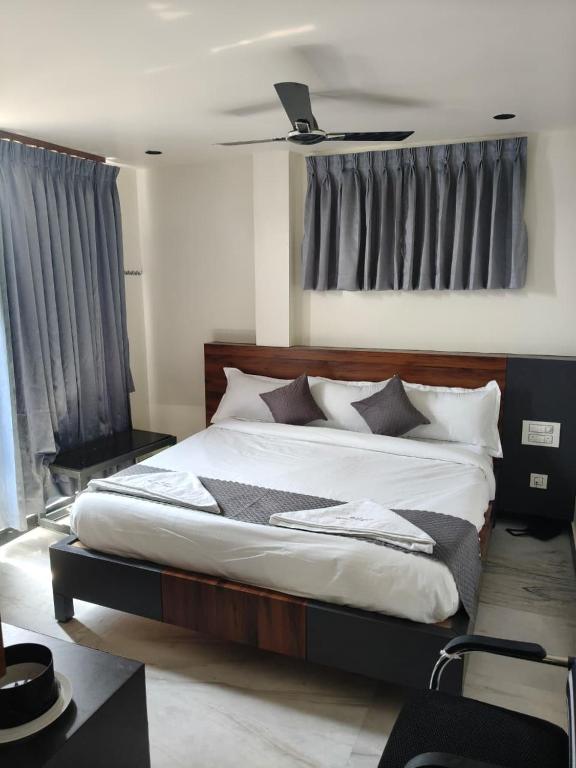 a bedroom with a bed with white sheets and pillows at Hotel Ambika Imperio in Vijayawāda