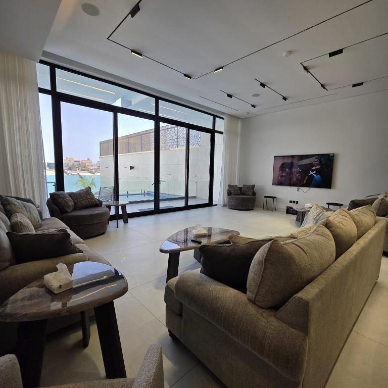 a living room with couches and tables and windows at ViLora VILA in Durat Alarous