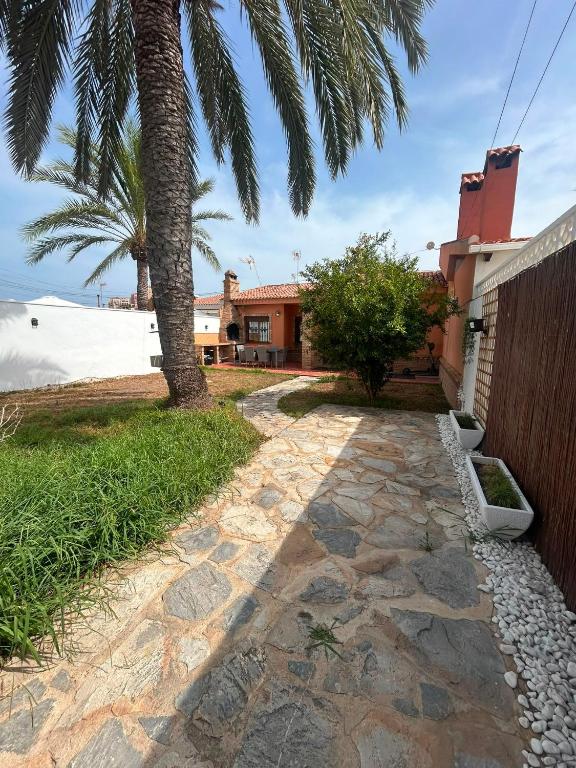 a stone walkway in front of a house with a palm tree at Chalet Los angeles torrevieja in Torrevieja