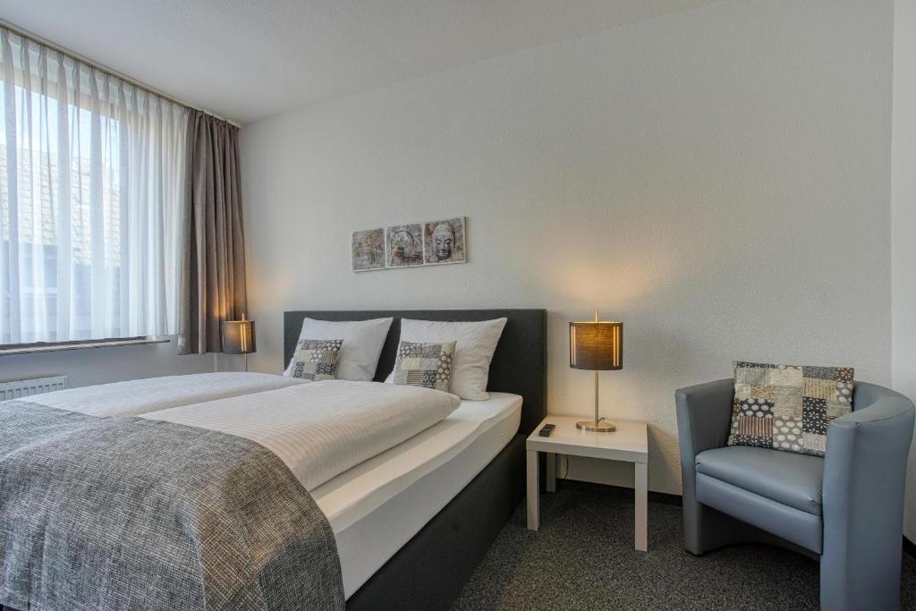 a bedroom with a large bed and a blue chair at Central Station Hotel Dortmund in Dortmund