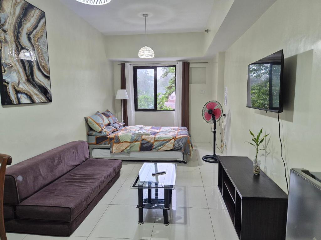 a living room with a couch and a bed at CozyNest Rentals at Brenthill Condominium in Baguio