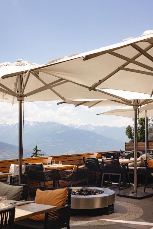 a restaurant with tables and chairs and umbrellas at Crans Ambassador in Crans-Montana
