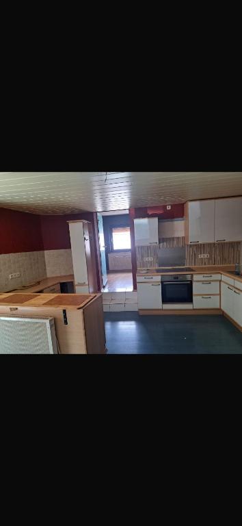 a large kitchen with white cabinets and a large window at Ferienwohnung Reckerche in Reckershausen