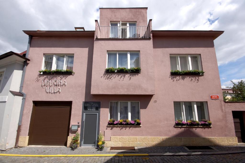 a pink building with windows and flower boxes at Libušina Villa in Kutná Hora
