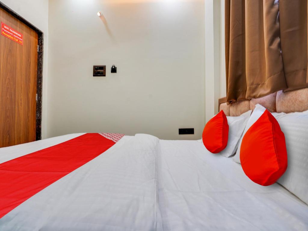 a bedroom with a bed with red pillows at Hotel O R.S in Nagpur