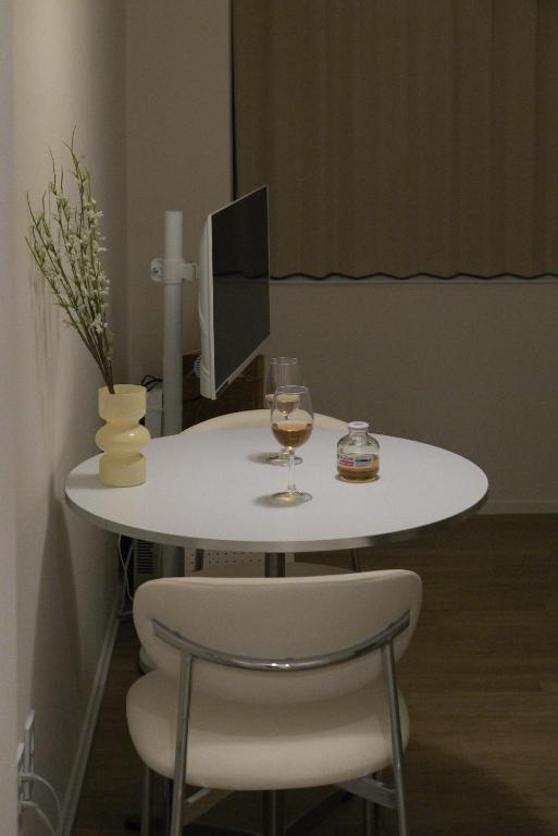a white table with a glass of wine and two chairs at 버터인 강릉역 중앙시장 월화거리 교리단길 도보 10분 in Gangneung