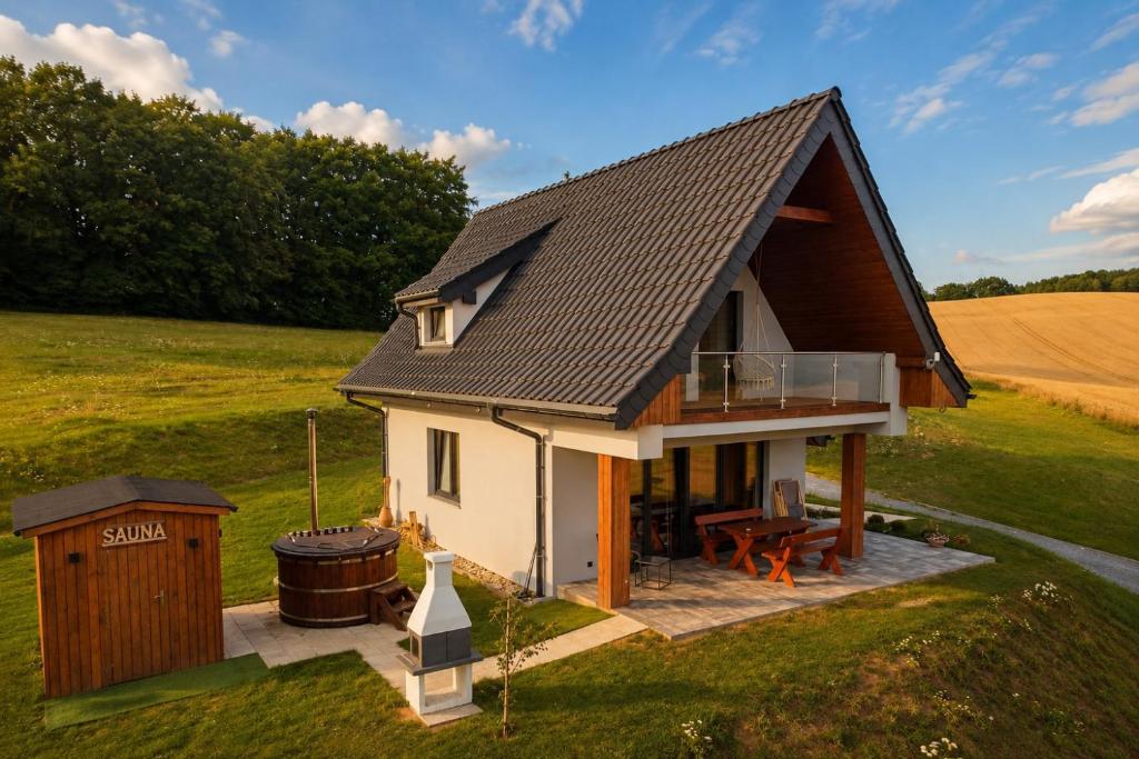 a small white house with a gambrel roof at W Sercu Kotliny - luksusowe wille z prywatnymi saunami, baliami i widokiem na góry in Kłodzko