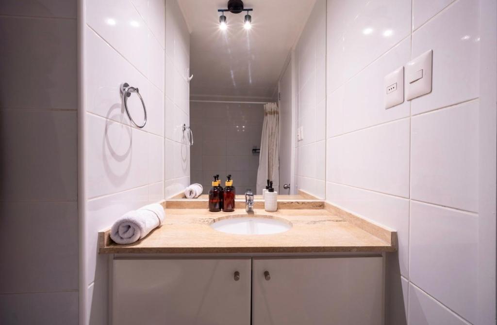 a white bathroom with a sink and a mirror at Suite moderna espacio parque in Calama