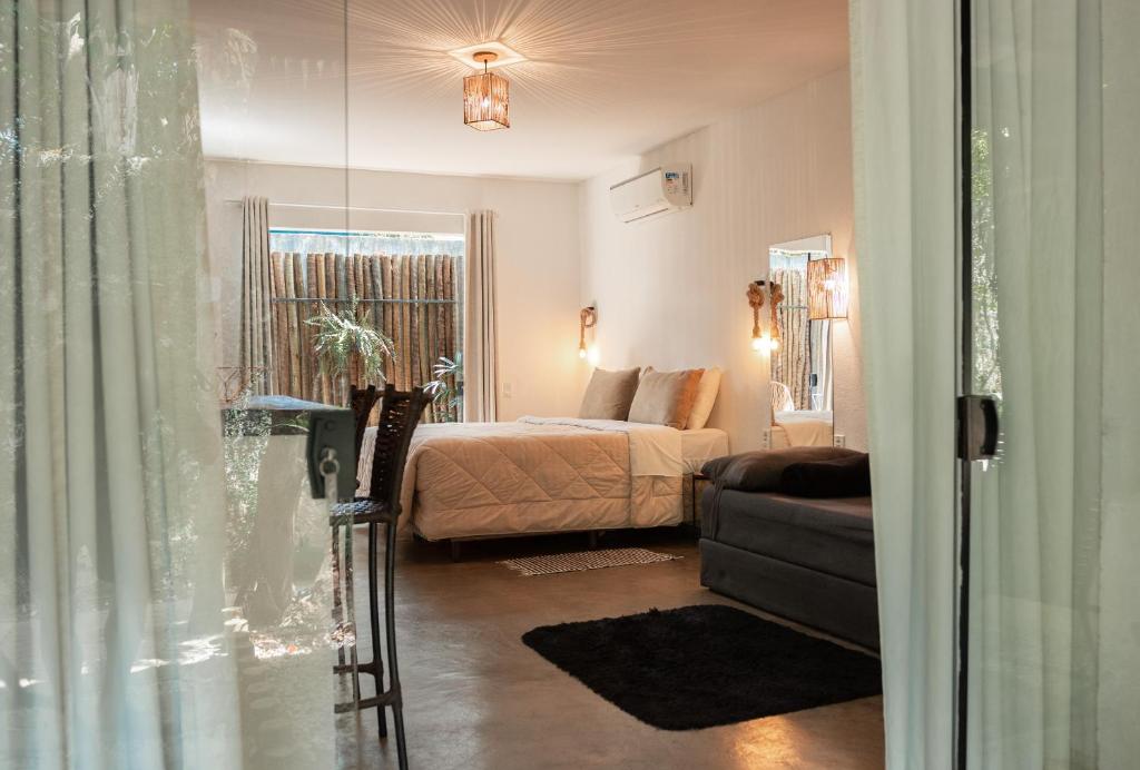 a bedroom with a bed and a couch and a window at Morada dos Saguis in Alto Paraíso de Goiás