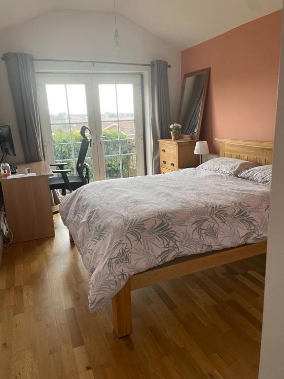 a bedroom with a bed and a desk and a window at Bright Double Room with Shared Bathroom in Luton