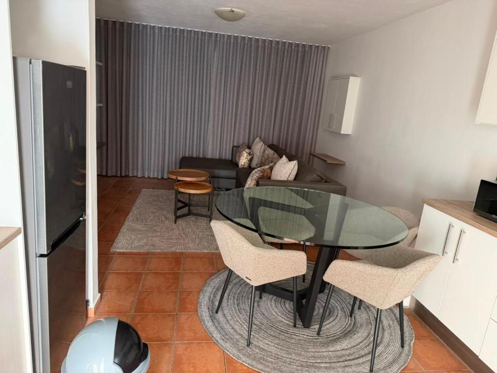 a living room with a glass table and chairs at Essie's Place in Windhoek