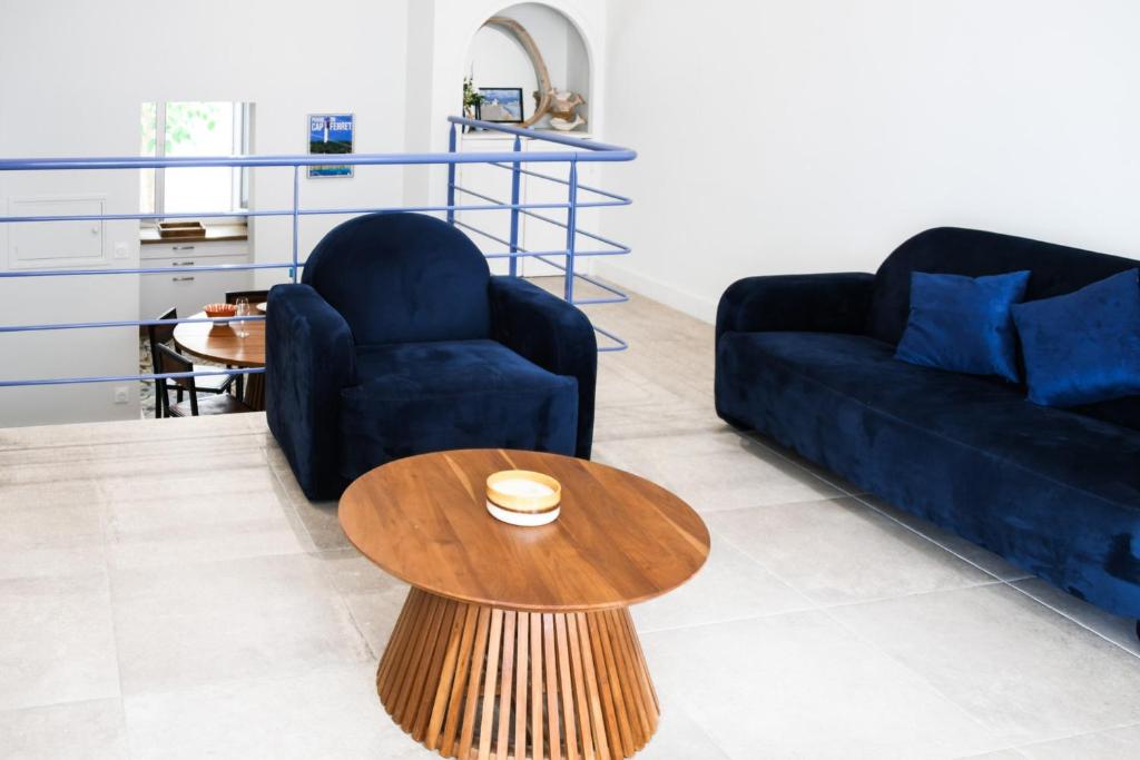 a living room with two blue couches and a wooden table at Villa Faraman au bord de l'eau in Le Grau-du-Roi